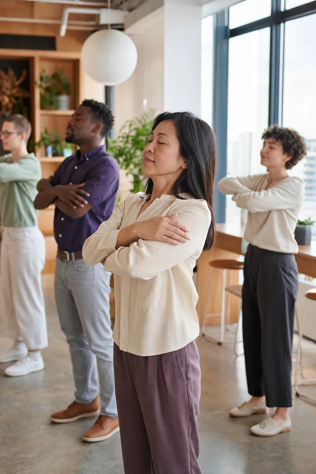 A multicultural team taking a calm standing wellness break together in their workplace common area. Illustrative image.